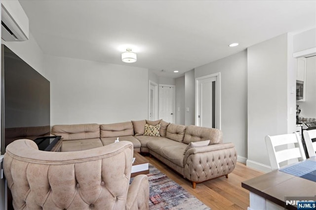 living area featuring light wood finished floors, recessed lighting, baseboards, and a wall mounted AC