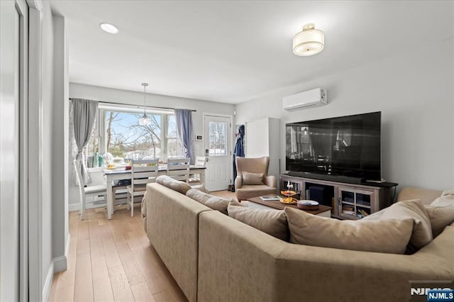 living area featuring a wall mounted air conditioner and light wood-style floors