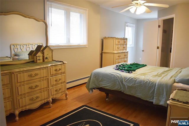 bedroom featuring light wood finished floors, a baseboard radiator, and ceiling fan