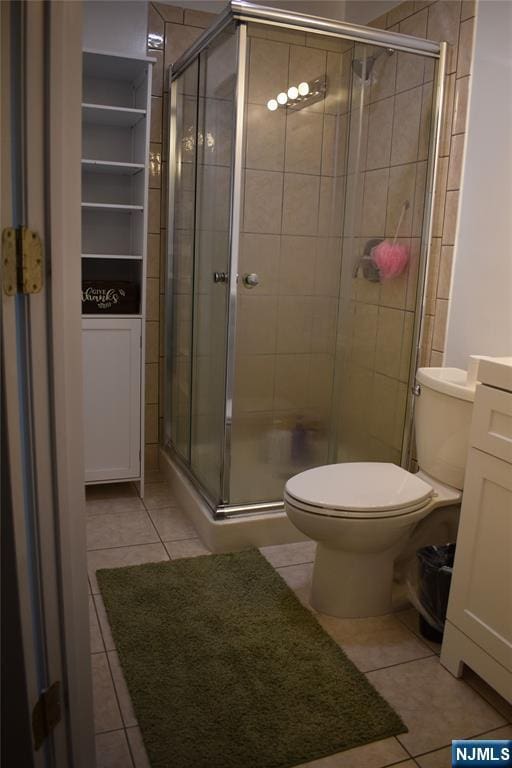 bathroom with a stall shower, vanity, toilet, and tile patterned floors