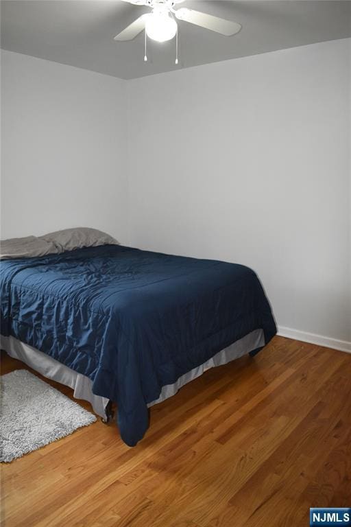 bedroom featuring baseboards, a ceiling fan, and wood finished floors