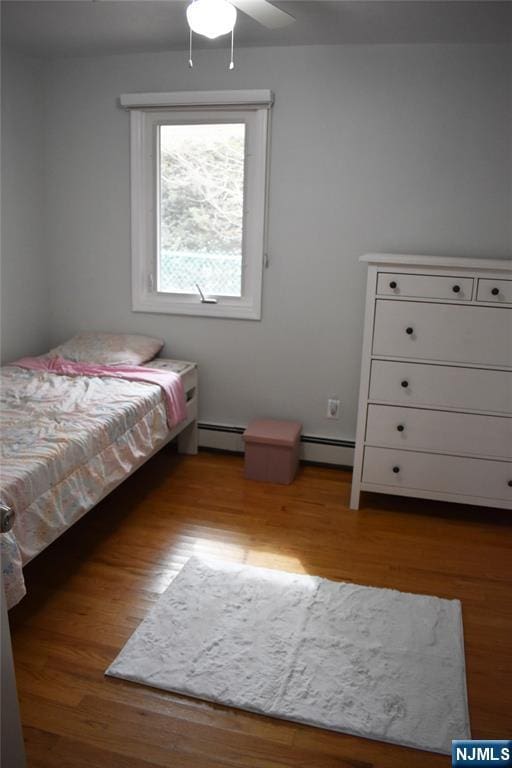 unfurnished bedroom with light wood-style floors, baseboard heating, and a ceiling fan