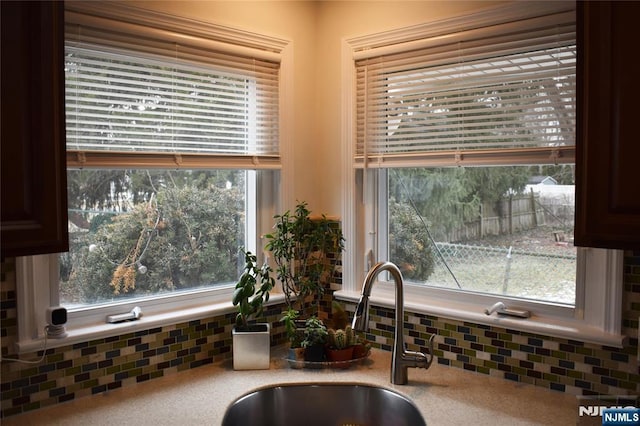 kitchen featuring light countertops, backsplash, and a sink