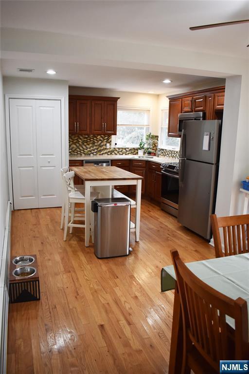 kitchen with light wood finished floors, butcher block countertops, appliances with stainless steel finishes, a breakfast bar area, and a center island