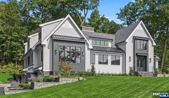 view of front of house featuring a standing seam roof, a front lawn, a chimney, and metal roof