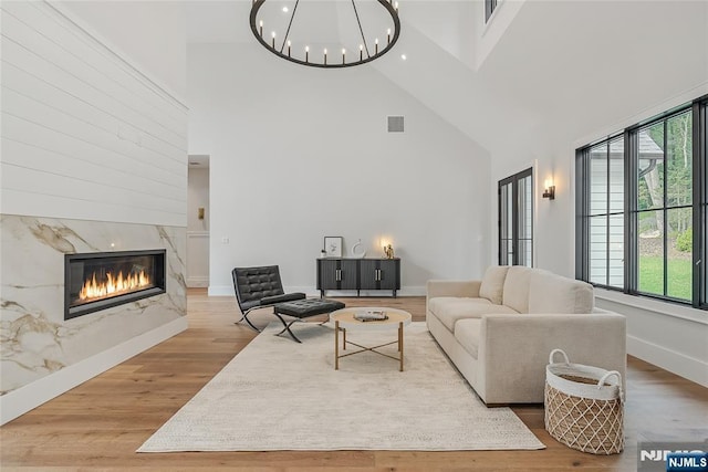 living area featuring visible vents, wood finished floors, a high end fireplace, an inviting chandelier, and baseboards