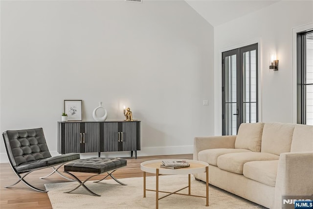 living area featuring lofted ceiling, wood finished floors, and baseboards