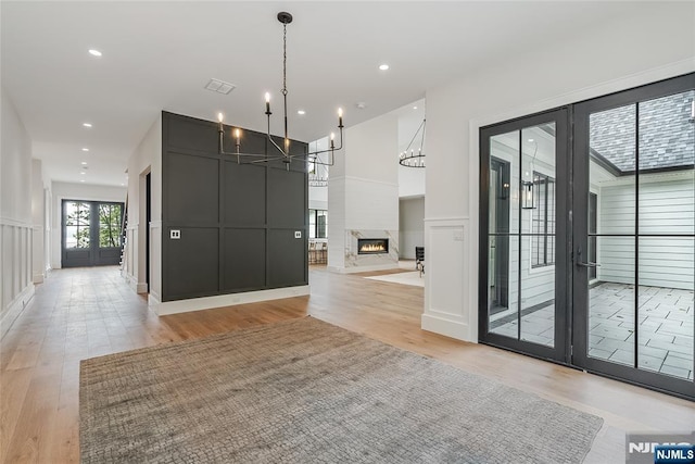 interior space with a chandelier, a decorative wall, and light wood-style floors