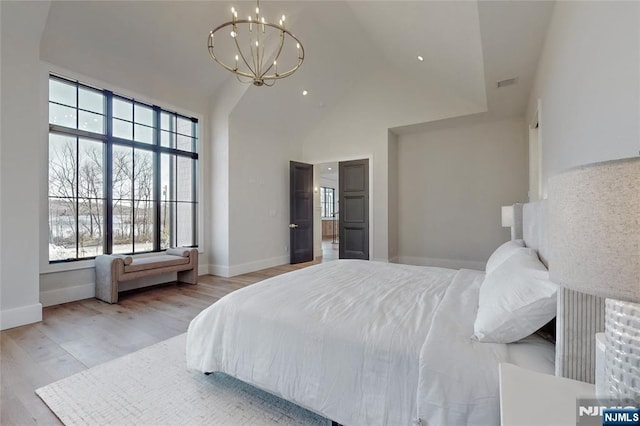 bedroom featuring wood finished floors, baseboards, visible vents, high vaulted ceiling, and a notable chandelier