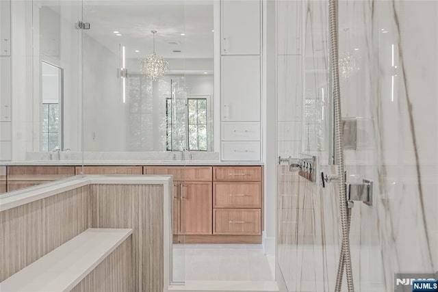 bathroom with tile patterned floors, a stall shower, vanity, and an inviting chandelier