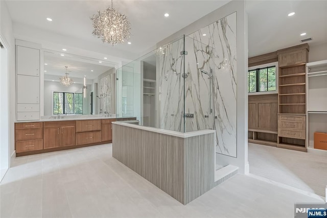 full bathroom featuring a marble finish shower, plenty of natural light, vanity, and an inviting chandelier