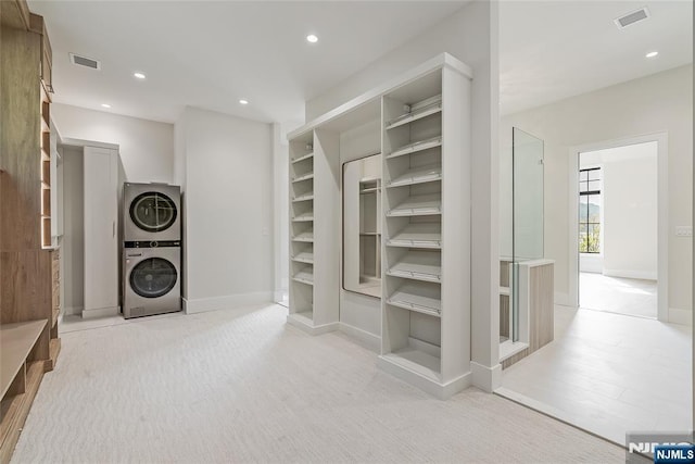 spacious closet featuring stacked washer / dryer, visible vents, and carpet floors