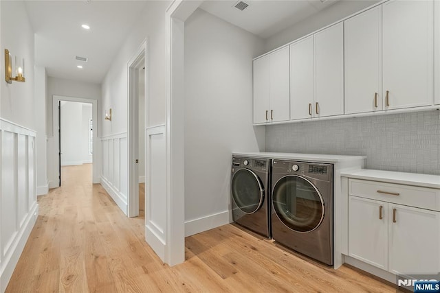 clothes washing area with recessed lighting, cabinet space, light wood-style flooring, and washer and clothes dryer