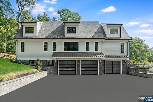 view of front of house with a front yard, a standing seam roof, a shingled roof, a garage, and aphalt driveway