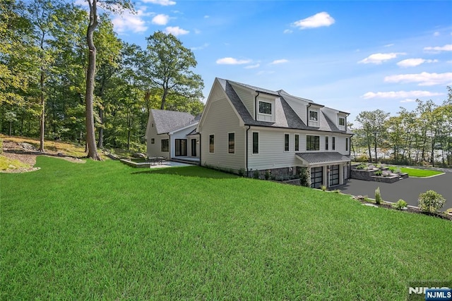 view of home's exterior featuring a yard, driveway, a shingled roof, and a garage