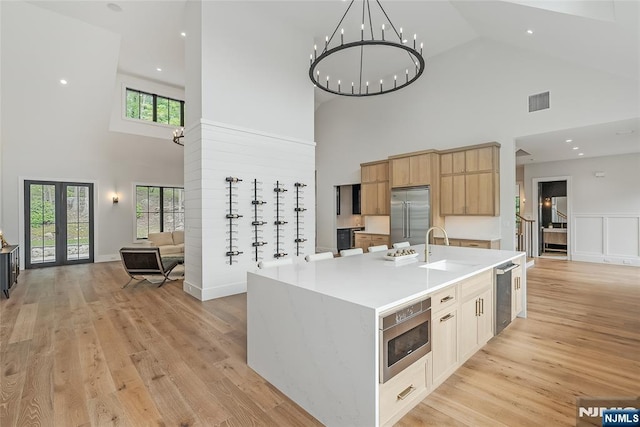 kitchen featuring light wood-style floors, open floor plan, built in appliances, and a sink