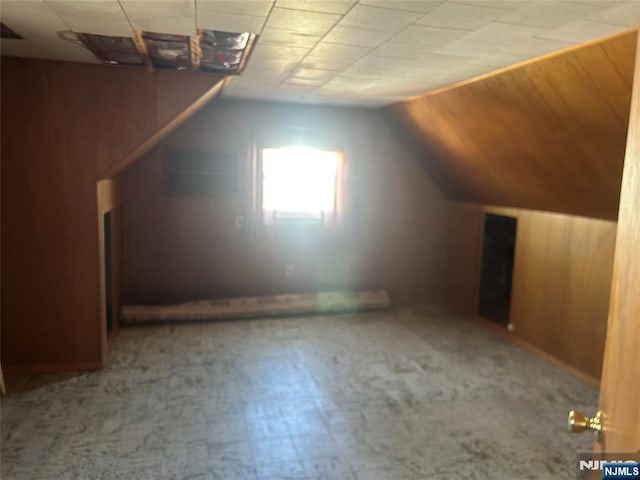 additional living space with lofted ceiling, wooden walls, and tile patterned floors