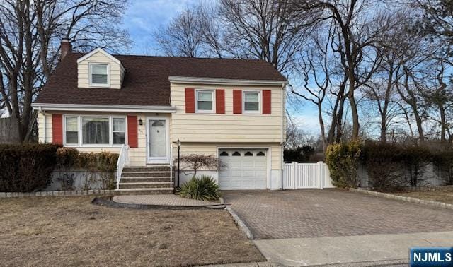 split level home with decorative driveway, fence, and an attached garage