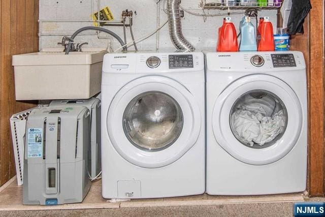 clothes washing area with laundry area, independent washer and dryer, and a sink