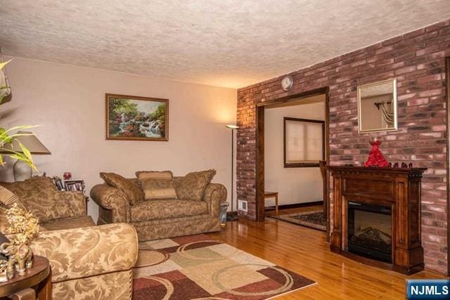 living area with a textured ceiling, a fireplace, and wood finished floors