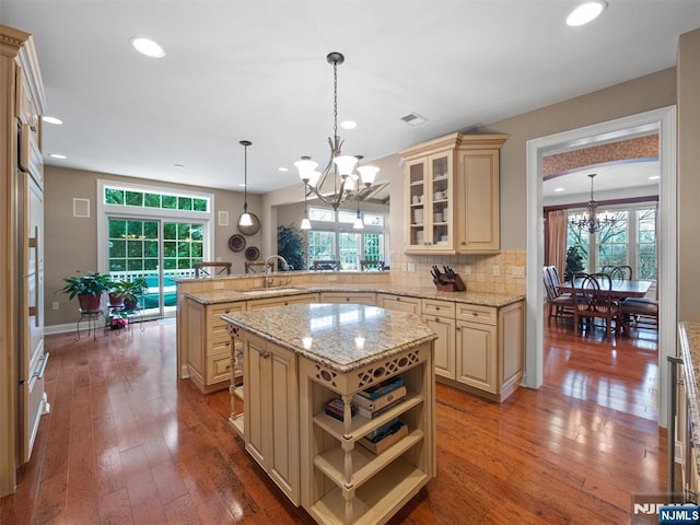 kitchen featuring decorative light fixtures, glass insert cabinets, a notable chandelier, and a center island