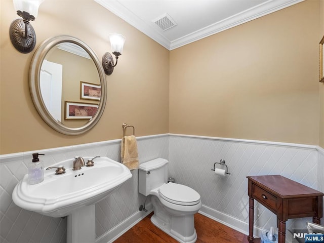 bathroom featuring toilet, visible vents, ornamental molding, and wainscoting