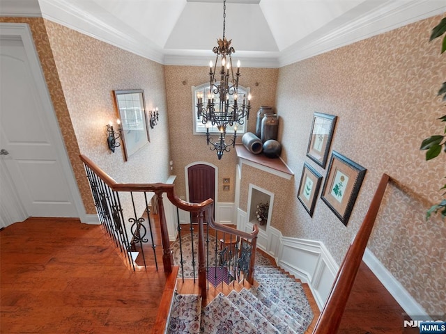 dining space with lofted ceiling, wood finished floors, wainscoting, wallpapered walls, and an inviting chandelier