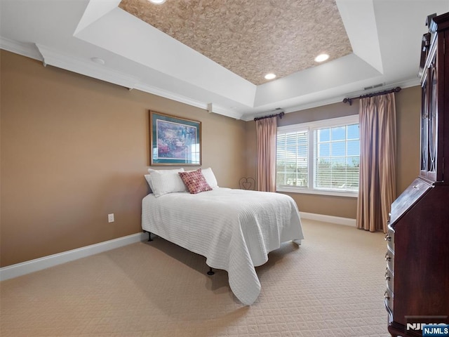 bedroom featuring light carpet, a tray ceiling, and baseboards