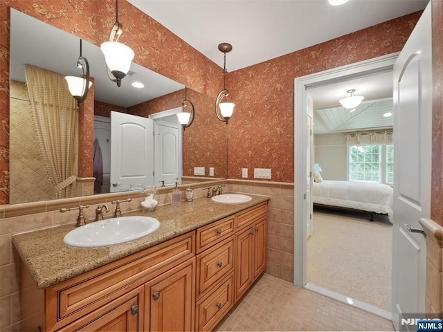 ensuite bathroom featuring a sink, wallpapered walls, and connected bathroom