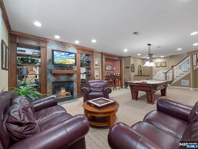 living room with ornamental molding, stairway, a tiled fireplace, and visible vents