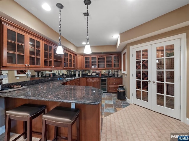 kitchen with hanging light fixtures, beverage cooler, glass insert cabinets, and dark stone countertops