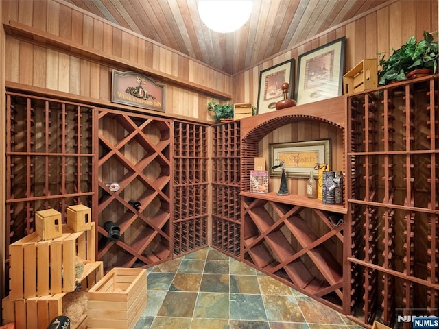 wine cellar with wooden ceiling, wood walls, and stone finish floor