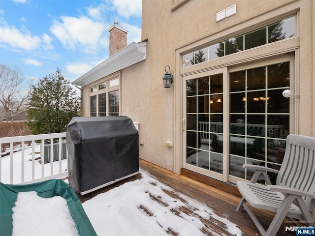 snow covered patio with area for grilling and a balcony