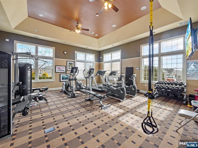 gym with a raised ceiling, carpet flooring, visible vents, and baseboards