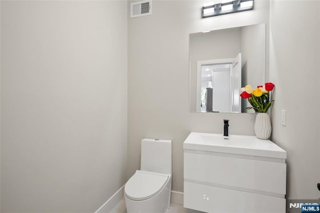 bathroom with baseboards, visible vents, vanity, and toilet