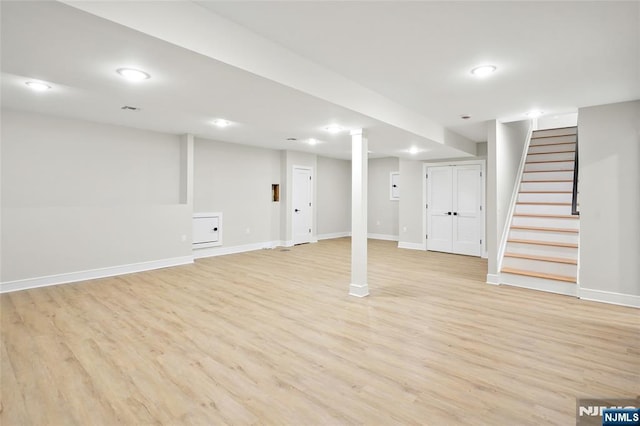 finished below grade area with baseboards, stairway, recessed lighting, and light wood-style floors