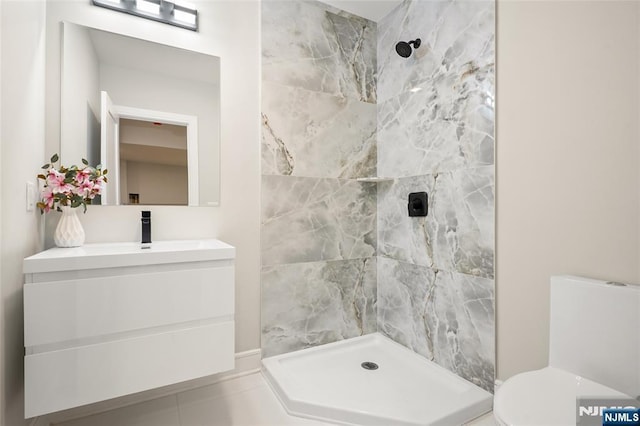 bathroom featuring vanity, a tile shower, and toilet