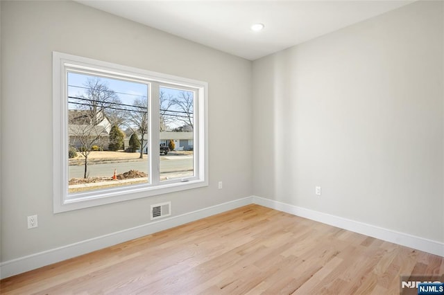 spare room with light wood-style floors, visible vents, and baseboards