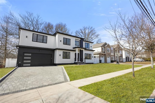 view of front of home with a residential view, an attached garage, fence, decorative driveway, and a front lawn