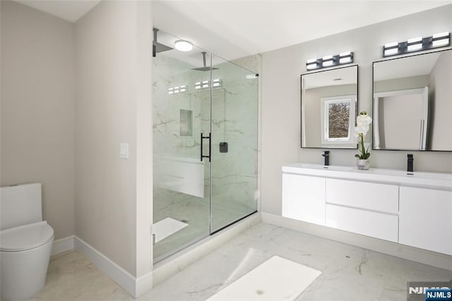 bathroom with toilet, a sink, baseboards, marble finish floor, and a marble finish shower