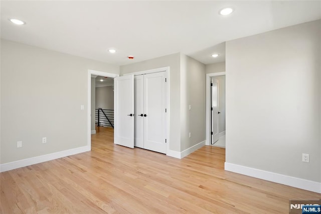 unfurnished bedroom with baseboards, a closet, recessed lighting, and light wood-style floors