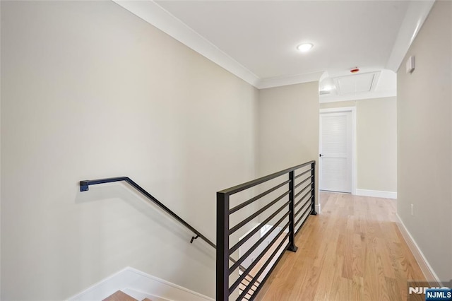 interior space featuring attic access, crown molding, baseboards, and wood finished floors