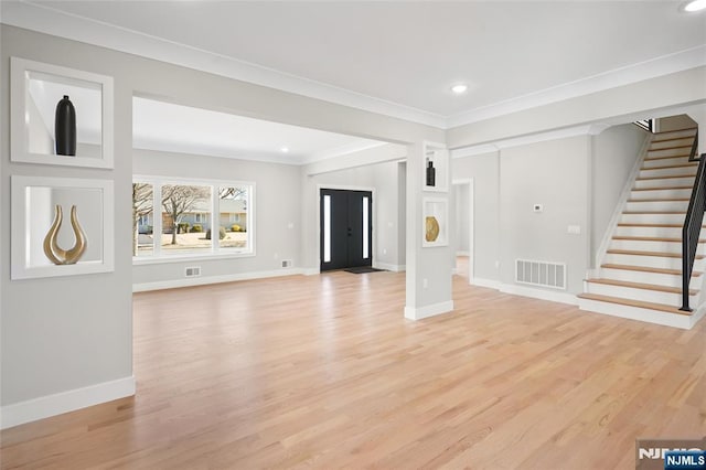 unfurnished living room with visible vents, stairway, light wood-style floors, ornamental molding, and baseboards