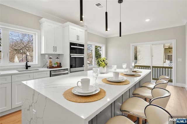 kitchen featuring light wood finished floors, visible vents, double oven, a kitchen island, and dishwasher