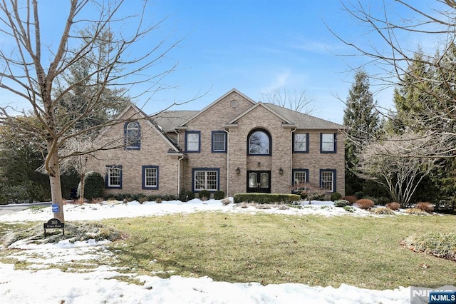 view of front of home with brick siding and a yard