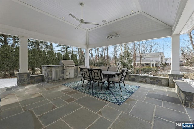 view of patio featuring grilling area, a ceiling fan, outdoor dining area, and exterior kitchen