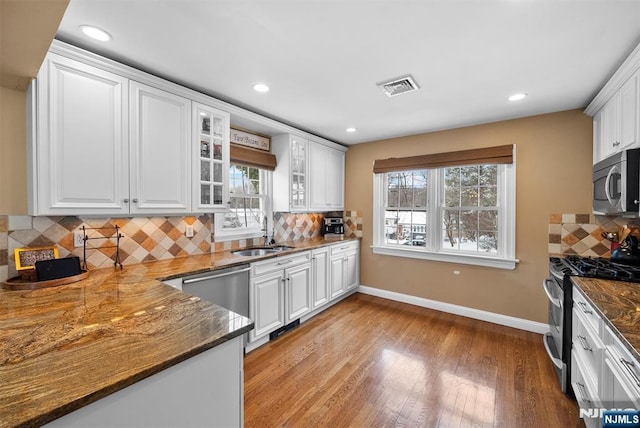 kitchen featuring white cabinetry, visible vents, glass insert cabinets, and stainless steel appliances