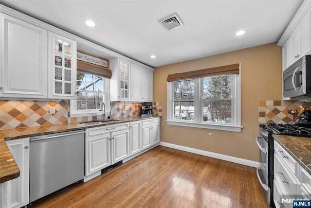 kitchen with white cabinets, glass insert cabinets, stainless steel appliances, and a sink