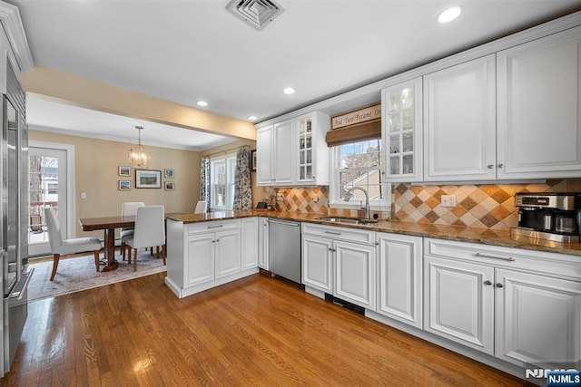 kitchen featuring decorative light fixtures, glass insert cabinets, white cabinetry, a sink, and dishwasher