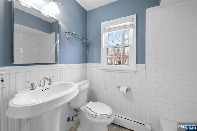 bathroom with wainscoting, a baseboard radiator, a sink, and toilet